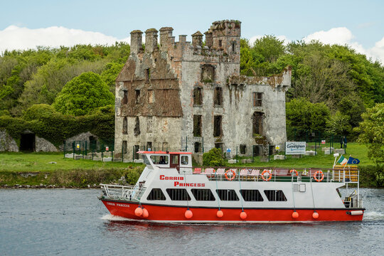 Galway, Ireland - 05.11.2022: Small cruise ship Corrib Princess with red and white color on river Corrib passing Menlo castle. Travel and tourism. Sightseeing Irish nature and history.