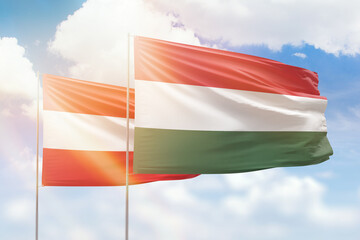 Sunny blue sky and flags of hungary and austria