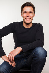 Portrait of young man in black shirt on chair