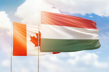 Sunny blue sky and flags of hungary and canada