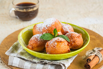 Deep fried round donuts on a green plate on a light concrete background. Deep-fried baking