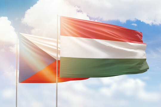 Sunny blue sky and flags of hungary and czechia