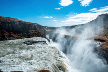 Idyllic view of Gullfoss waterfall in Golden Circle. Scenic cascades of falling water against blue sky. Beautiful scenery of natural rock formations in dramatic landscape.