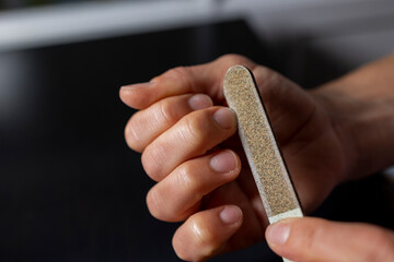 A woman files her nails with a natural nail file close-up. Women's natural, natural nails and nail...
