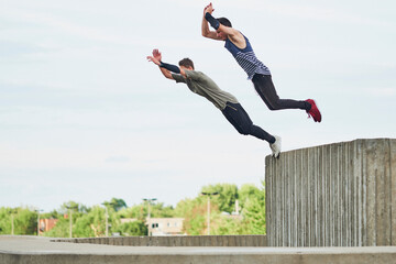 Teenage free runners jumping off concrete structure
