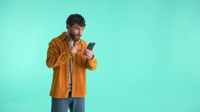 Anticipating guy looking at smartphone's screen while expecting for bet results, becoming winner rejoicing, showing yes gesture of victory. Lucky male expressing success and win in online betting
