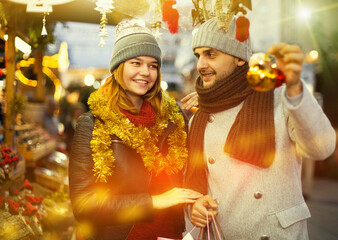 Positive young couple buying decoration at Christmas Fair outdoor