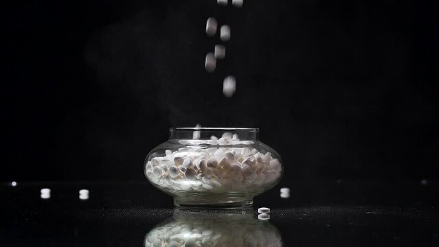 Random Pills being dropped into an antique jar in slow motion 120fps 1080p with pills flying around.
taken on a mirror surface with a black backdrop in a studio setup with a single light