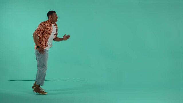 Expressive dark-skinned man running on same spot pretending to be in a hurry. Man looking at wrist watch and speeding up to not be late for discounts or sales, studio shot isolated on background