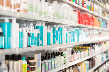 Bottles and boxes of different hair care products on store shelves in supermarket
