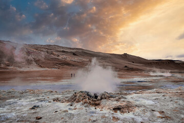Scenic view of steaming fumarole in geothermal area of Hverir. Sulphur dioxide emitting from volcanic crater at Namafjall. Geyser in famous tourist attraction against sky during sunset.