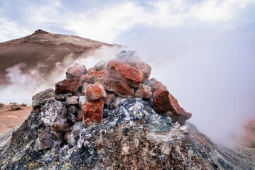 Close-up of steaming fumarole in geothermal area against cloudy sky. View of Sulphur dioxide...