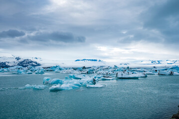 Beautiful icebergs floating in glacial lake. Scenic view of glacial ice formations against cloudy sky. Idyllic scenery of Jokulsarlon glacier lagoon during polar climate.