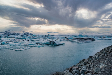 Idyllic view of Jokulsarlon glacier lagoon against dramatic sky. Beautiful icebergs floating in lake. Scenic view of frozen glacial ice formations in water at in Vatnajokull during sunset.
