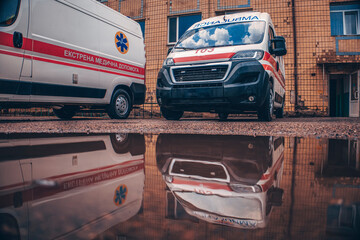 Ambulances are reflected in a puddle. The inscription Ambulance. © Олег Мальшаков