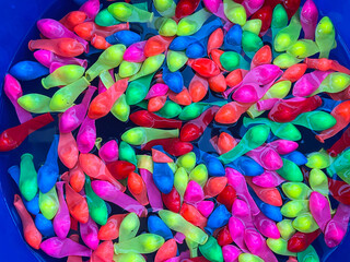 bucket full of water and deflated water balloons floating, balloon texture, vivid colors, summer games, water balloon warfare