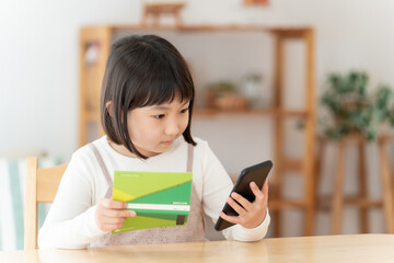 預金通帳とスマートフォンを見つめる女の子