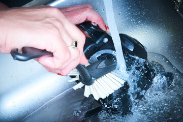 Female hands washing dslr camera as dirty dishes running water in the sink. Crazy photographer poorly cleans the camera sensor with water