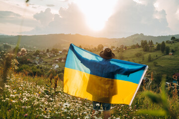 successful silhouette man winner waving Ukrainian flag on top of the mountain peak
