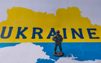 Metal figurine of a soldier on the background of the map of Ukraine.
