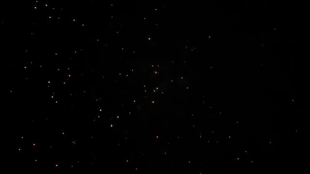 Colorful bright fireworks in dark sky at night: slow motion. Evening time, low light. Abstract, holiday, entertainment, celebration and anniversary concept
