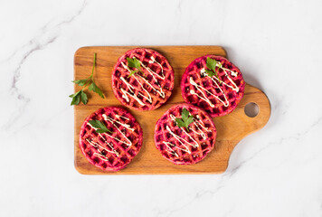 Vegan Small round beetroot waffles, on a wooden board. Light background. Top view
