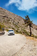 Car climbing on winding mountain road on the hot island of Santorini.