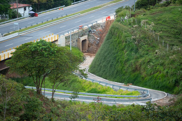 Narrow Road under a Bridge where Cars Pass and a Tunnel Under Construction with a Lot of Mud