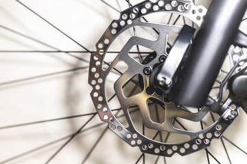 Front hydraulic disc brake on a mountain bike on a black fork and spokes from the wheels, close-up