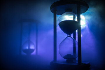 Time concept. Silhouette of Hourglass clock and old vintage wood clock with arrow and smoke on dark...