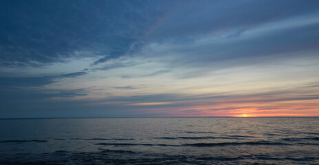 Baltic sea at sunset. Dramatic sky, blue and pink glowing clouds, soft golden sunlight, midnight...