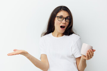 portrait of a surprised, emotional, beautiful, attractive middle-aged brunette woman in glasses and a white tank top, holding a cup