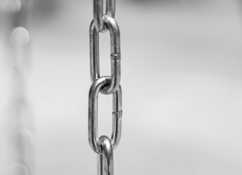 Diagonal, partial blurred iron chain on blurred background. Low angle view of steel chains.