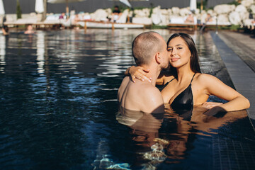 Fototapeta na wymiar A beautiful love couple on vacation day in pool having great lover time