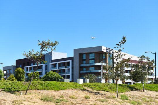 TUSTIN, CALIFORNIA - 12 JUN 2022: Apartments on Redhill Avenue with jet airplane on final approach to John Wayne Airport.
