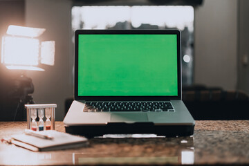 Laptop with green screen for adding images. In the background a notebook with a background of lights