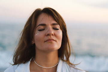 Portrait of a happy young girl with closed eyes on a background of beautiful sea. The girl looks at the magical sea. Freedom and happiness