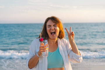 Portrait of a happy young girl with a cocktail in hand on a background of beautiful sea. Girl...