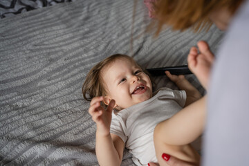 One small caucasian girl toddler lying on the bed at home while her mother is changing diapers real...