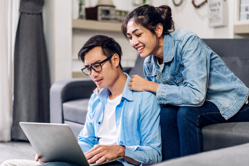 Obraz premium Young asian couple relaxing using laptop computer work and video conference meeting online chat.Creative business couple planning strategy analysis and brainstorm at home