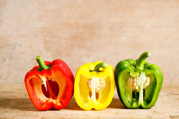 Sweet red, yellow, green peppers on wooden background.