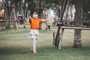 Asian children with face mask wear orange t-shirt play in playground. Concept for funny and active activity of kid.