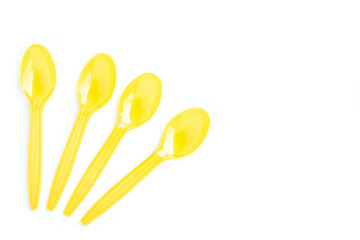 Yellow plastic spoons on white background