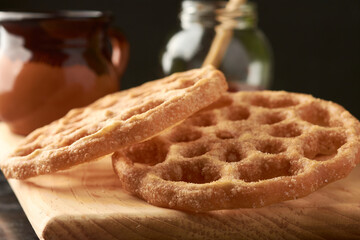 Mexican buñuelos or puñuelos with a circular shape, at the bottom coffee and honey to enjoy, placed on a wooden base.