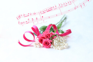 ホットピンクのバラの花束と真珠とリボンと楽譜の合成	