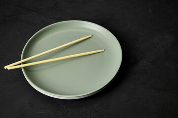 grey plate and chopsticks on a black background