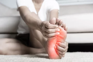 Abwaschbare Fototapete Spa Foot pain, Asian woman feeling pain in her foot at home, female suffering from feet ache use hand massage relax muscle from soles in home interior, Healthcare problems and podiatry medical concept