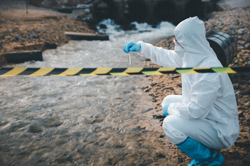 Scientist or Biologist in a protective suit and protect mask collects sample of waste water from industrial for analyze, problem environment, Ecologist sampling water from the river with test tube