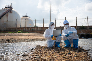 Biologist wear protective suit and mask collects sample of waste water from industry, problem environment, Ecologist sample taken dead fish to inspection and save data to laptop computer, Toxic water