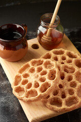 Mexican buñuelos or puñuelos with a circular shape, at the bottom coffee and honey to enjoy, placed on a wooden base.